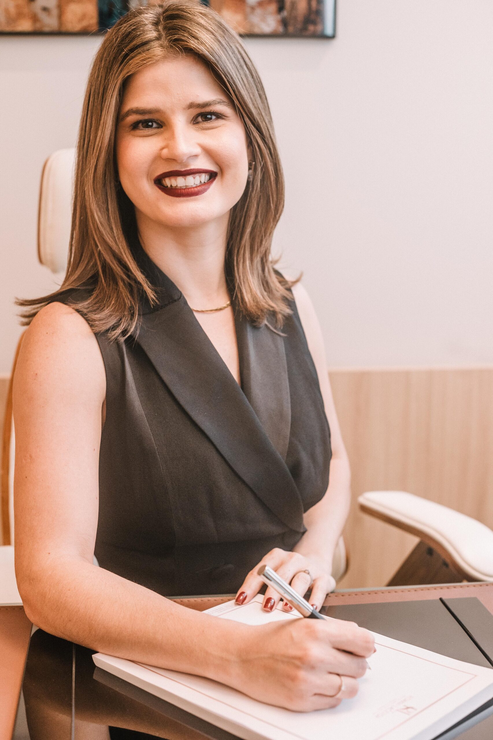 Dra. Roana Lacerda, Cirurgiã Vascular e Endovascular, sorrindo em seu consultório moderno na Barra da Tijuca, Rio de Janeiro.